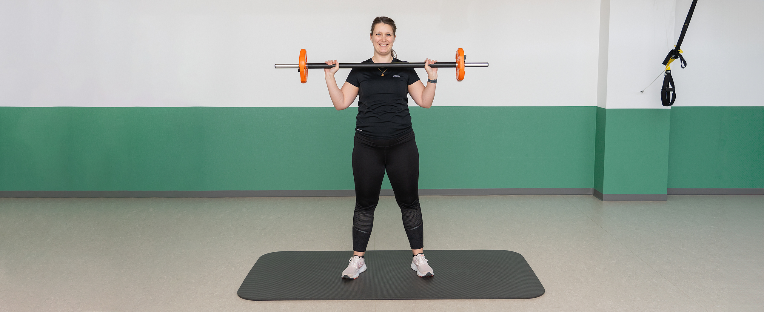 Fysioterapeuten laver squat med bodybar